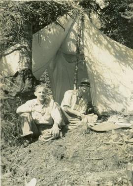 Two unidentified men sitting at the entrance of a tent