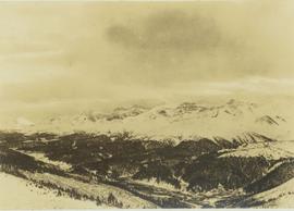 Snow-covered mountain range and forested foothills below