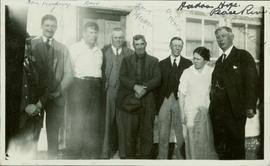 Group photo featuring eight people standing outside a home in Hudson Hope