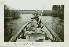 Three men seated in the stern of a boat sailing on Crooked River