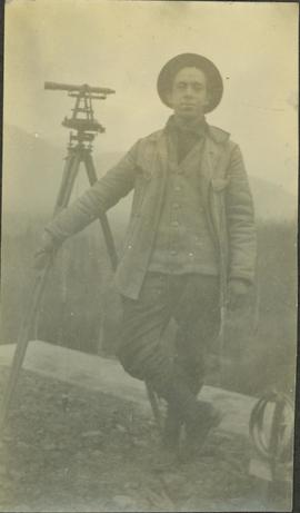 R.A. Harlow (?) standing next to a leveling instrument