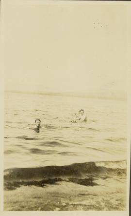 Three men swimming in a lake