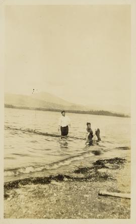 Two fully clothed men wading into a lake