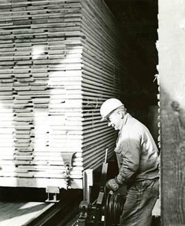 Workman with stack of lumber