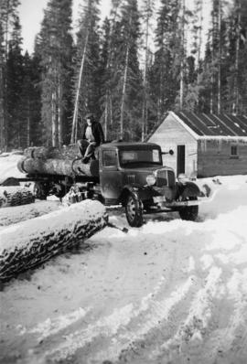Man atop a log truck in winter at Peden Hill sawmill