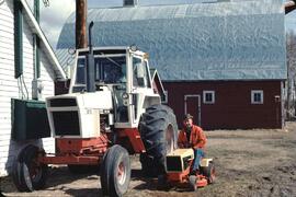Billy on lawnmower next to Joan Sawicki in tractor at the Runka farm in Fort St. John