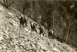 Soldiers hiking single file on rocky slope