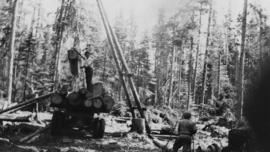 Loggers using a gin pole, winch and jammer to load logging truck