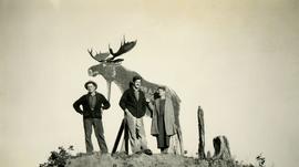 Jack Lee, Gordon Wyness, and Lavender Monckton in front of wooden moose in Prince George
