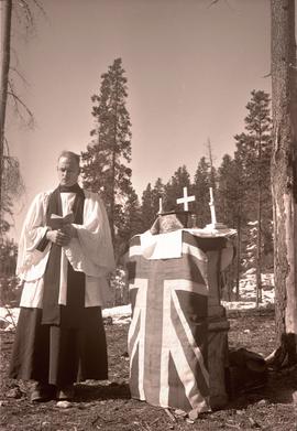 Military chaplain reading by a makeshift altar with the Union Jack