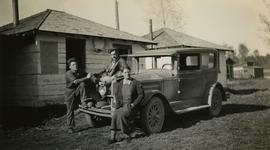 Jack Lee, Gordon Wyness, and Lavender Monckton sitting on car in front of Prince George cabin