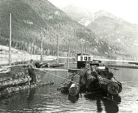 Log raft guided through log boom by a boom boat and workman