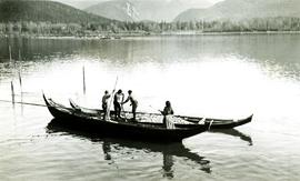 Unidentified men and woman standing in canoes: Oolichan fishing on Nass River, BC