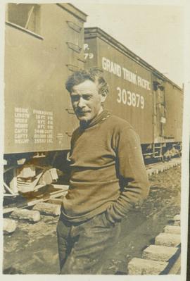 Unidentified man standing next to Grand Trunk Pacific railcars