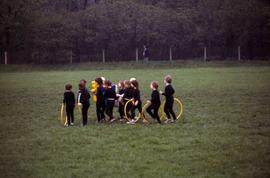 Young children with hula hoops on a field in East Germany