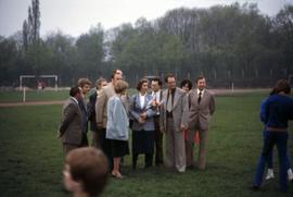 Iona Campagnolo holding flowers with unknown people in a sports field in East Germany