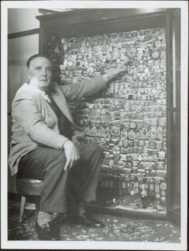 A man posing with a collection of R.I.C. badges