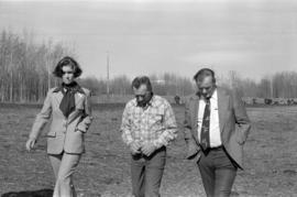 Iona Campagnolo, Minister Jack Horner, and unidentified other walking through a cow pasture in Smithers