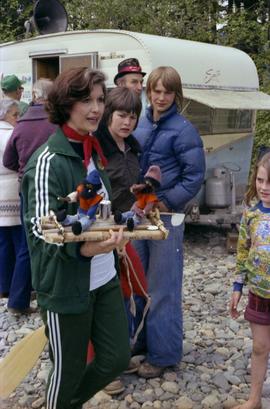 Iona Campagnolo holds handmade rafting figurines at Kitimat Delta King Days raft event with unidentified children