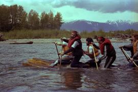 Iona Campagnolo and unidentified men paddling raft on Kitimat River during Delta King Days event