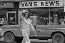 Iona Campagnolo waving to crowd in front of Van's News store while walking in parade in Smithers