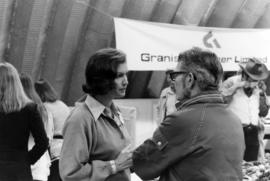 Iona Campagnolo talking to man in front of banner for Granisle Copper Limited