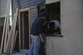 Assistant to Iona Campagnolo and man work on a window frame in a house under construction