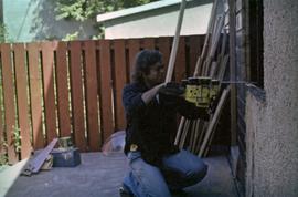 Man with chainsaw cutting window frame in house under construction