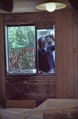 Assistant to Iona Campagnolo and man install a window in a house under construction