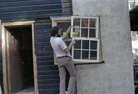 Assistant to Iona Campagnolo holding window in a house under construction