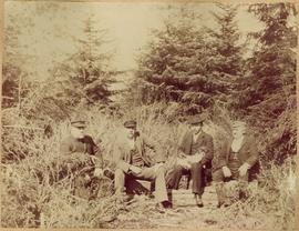 Four Men Seated on Log in Forest