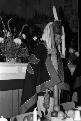 Dempsey Collinson wearing button blanket and head dress and holding a carved staff in Skidegate