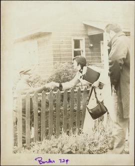 Iona Campagnolo reaching over a fence to shake hands with W. Neil Sterritt in his front yard in M...