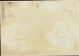 Distorted image of Iona Campagnolo talking to an unidentified man on the patio of unknown house