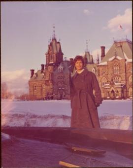 M.P. Iona Campagnolo posing in front of Parliament buildings in Ottawa, winter 1976
