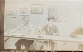 Iona Campagnolo speaking at long table as two men listen, 1976