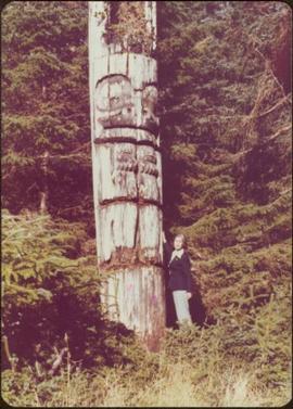 Iona Campagnolo posing beside a carved memorial pole, Ninstints, Anthony Island, Haida Gwaii, Sep...