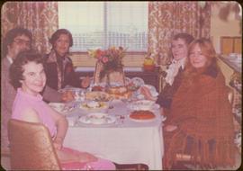 Eve Rockett, Mike?, Minister Iona Campagnolo, Juanita Holton, and Tillie Laplante around a set table in curtained living room