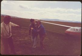 Skeena Riding tour - Iona Campagnolo and two unidentified men pulling a glider through a field with a rope