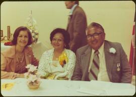 Iona Campagnolo, Mrs. Ivy Maitland, and Heber Maitland seated at table in Kitamaat, BC