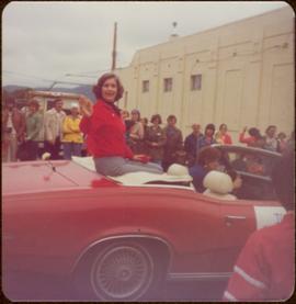 Iona Campagnolo waves from the back of a red convertible as she is driven through parade