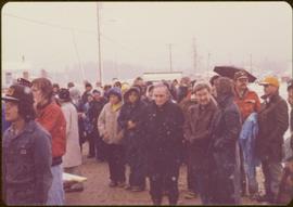 Raising of Eli Gosnell’s Pole, New Aiyansh, November 1978 - Iona Campagnolo stands outside in snow with crowd of unidentified people