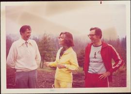 Minister Iona Campagnolo wears a jogging suit while standing outside with two unidentified men, K...