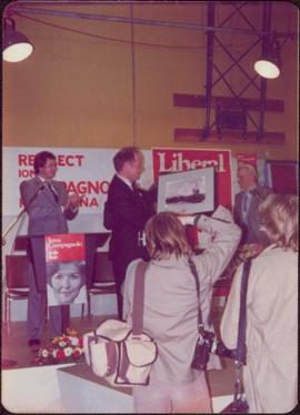 Prime Minister Pierre Trudeau accepts a painting of a fishing boat on stage at Campaign opener in Smithers, BC