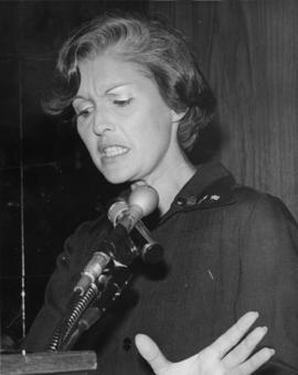 Iona Campagnolo gesturing with hand while speaking at microphone in Liberal publicity image
