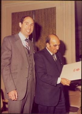 Paris Press Conference - Roger Jackson stands smiling next to an unidentified man holding a Calgary folder