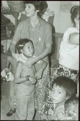 CUSO Mission, North-eastern Thailand - Unidentified woman putting a shirt on a young girl in front of other young children