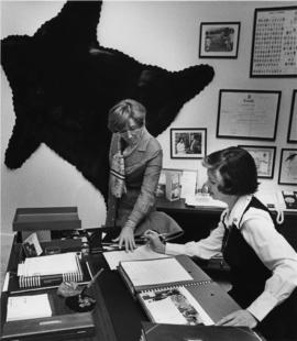 Iona Campagnolo and assistant in office with black bear on wall