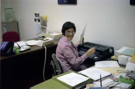 Woman at typewriter behind desk in an office