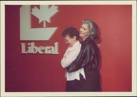 Iona Campagnolo hugs Rita Jauharne at 102 Bank St. in front of a Liberal sign in Ottawa, ON